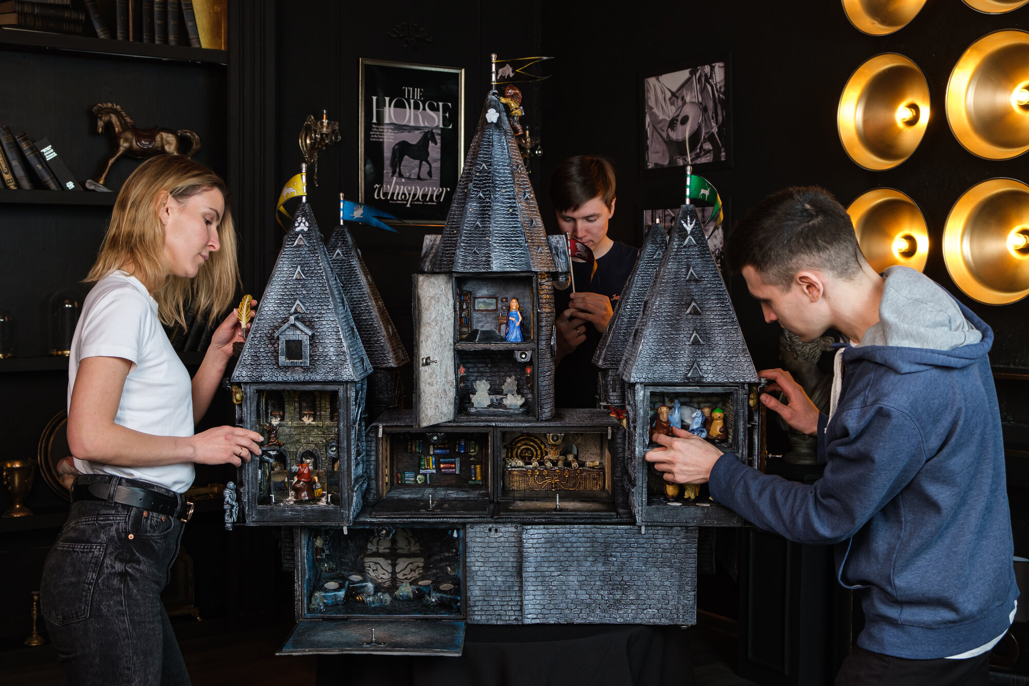 Craftspeople inspecting a highly detailed handmade escape-room castle prop, showing the build quality behind the cost